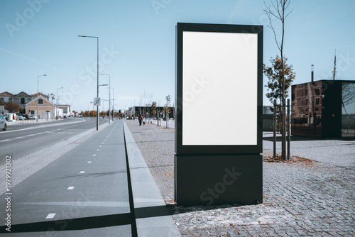 Blank roadside billboard mockup on sunny urban street, vertical advertising display template beside bike lane and sidewalk, with copy space, modern city setting and clean perspective
