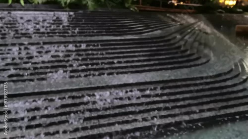 Blurred Flowing water over urban landscape steps, gentle ambient water sound, modern city architecture B-roll for commercial use.