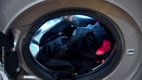 Hand placing dirty laundry into washing machine, interior view
