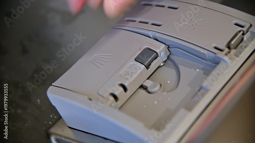 Person places tablet into dishwasher compartment for cleaning and maintenance