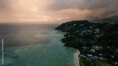 Beautiful sunset casting orange hues over multiple islands and calm ocean waters, with silhouetted hills. Seychelles, Mahe.