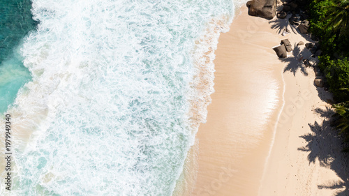 Waves crashing on the sandy coastline with palm shadows on the shore. Seychelles, Mahe.