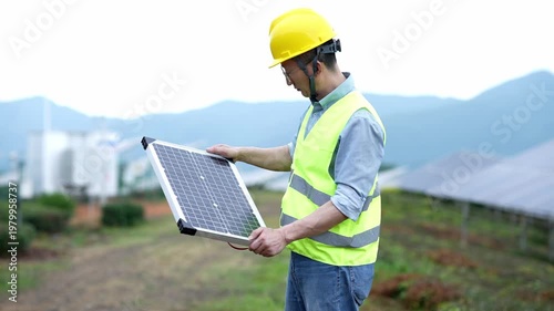 Engineer inspecting a handheld solar panel on-site at a mountainous photovoltaic farm