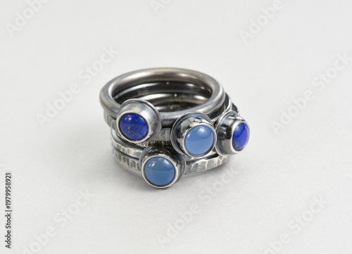Darkened silver rings stack on white background. Hand made sterling silver rings with round blue cabochon gemstones, like lapis lazuli and blue chalcedony. Silver jewelry darkened using oxidisers.