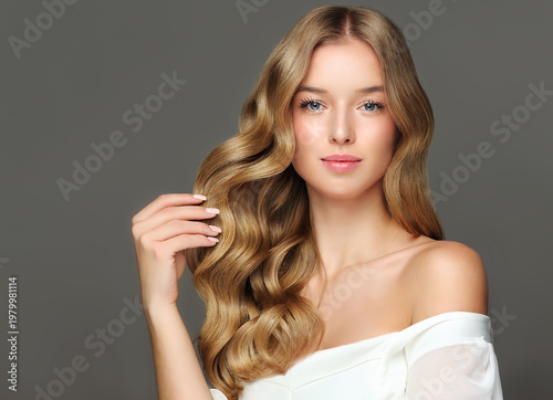 Beauty blonde girl with long and shiny wavy Hair ,coloring and toning, shatush , air touch and balayash . Beautiful woman model with curly hairstyle . Beauty salon and barbershop . Hair curling 

