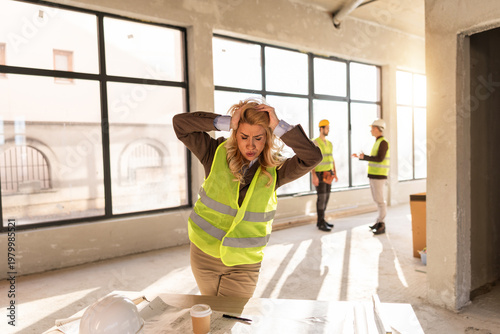 Tableau sur toile Workers discuss project progress while a woman expresses frustration in a constr