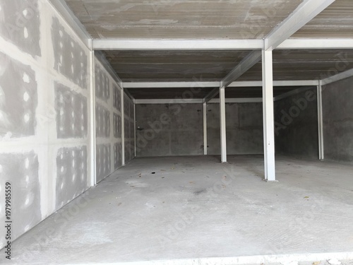 Empty concrete garage or storage unit under construction with steel frame. Industrial storage unit, a home garage under renovation, or a commercial warehouse shell