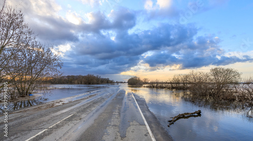 Dusk floodwaters surround a deserted road through wetlands