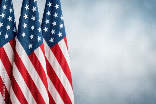 Three american flags with red, white, and blue stripes and stars arranged vertically against a soft blurred gray background