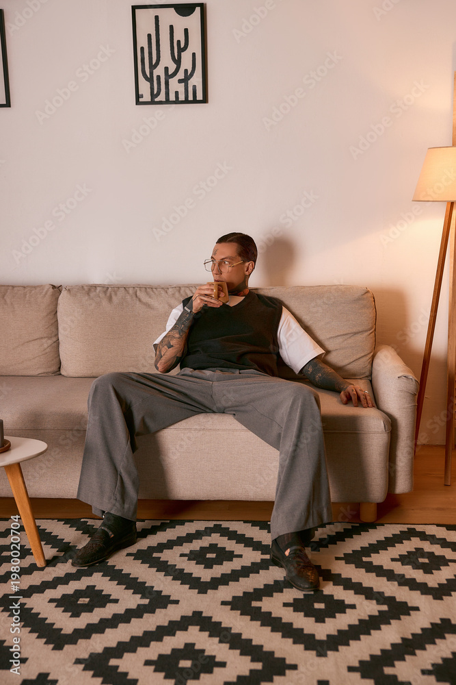 Fototapeta premium Stylish young man relaxing on a couch in a cozy living room with modern decor