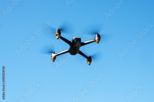 Industrial drone flying in clear blue sky. Modern technology for game, delivery or work.