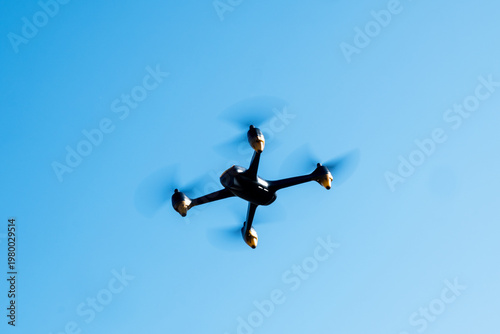 Industrial drone flying in clear blue sky. Modern technology for game, delivery or work.