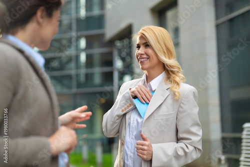 Obraz na plátně Businesswoman smiling while hiding a blue envelope received from a colleague