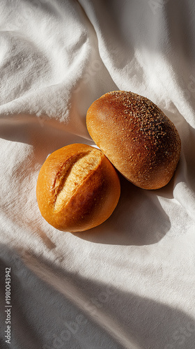 Freshly baked bread rolls on a white cloth, showcasing golden crust and soft texture