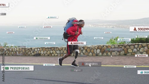 African American midadult man running along coast road with pack, UI tags showing, using prosthetic