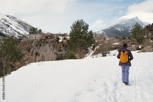 A girl hiking along a snow-covered trail in a mountainous landscape. In the Pyrenees in Spain.