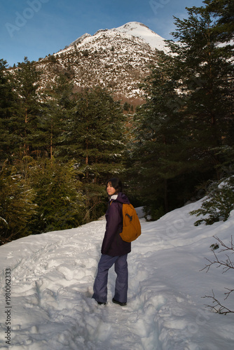 A girl hiking along a snow-covered trail in a mountainous landscape. In the Pyrenees in Spain.