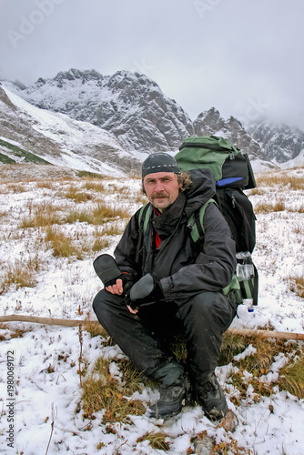 Hiker in winter gear poses in mountainous terrain
