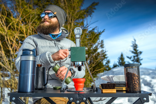 Portable manual espresso maker brewing coffee outdoors in winter mountains camping setup