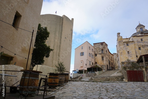 street in the old town of calvi, corsica, france by the plaza and the church, with some old wooden wine barrels as tables