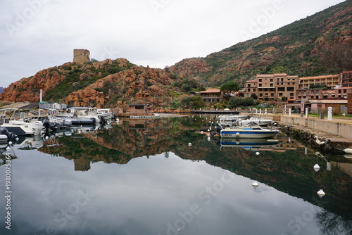 panoramic view of the town of porto on the island of corsica, france with the harbor and the old stone tower and mirror reflection