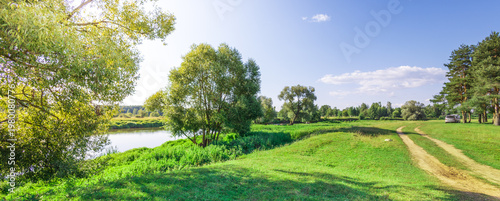 Wallpaper Mural Lush green grass slopes gently to a calm riverbank Torontodigital.ca