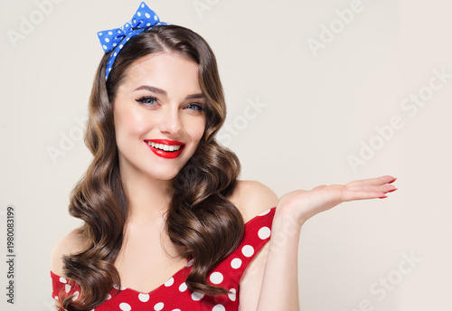 A Pin Up young smiling woman in a retro outfit points to the side, showcasing an invisible Presenting your product .Beautiful vintage girl with curly hair  .Expressive facial expressions