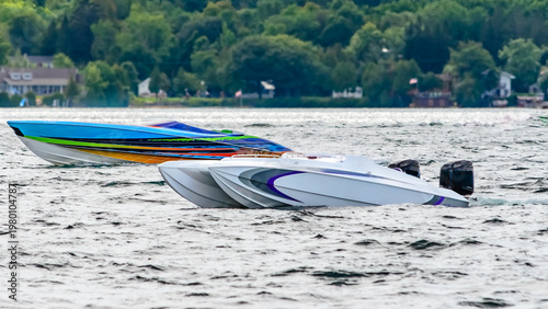Two speedboats anchored in choppy water with treelined shore in the background.