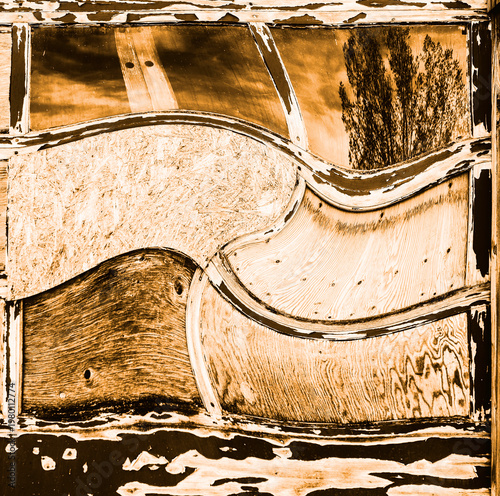 Old wood garage door has been distorted. You see wood patches everywhere. I looks like a construction world in disarray or turned upside down.