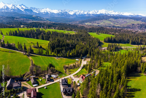 Aerial view of Tatra mountains peaks over green meadows in Lapszanka, Poland
