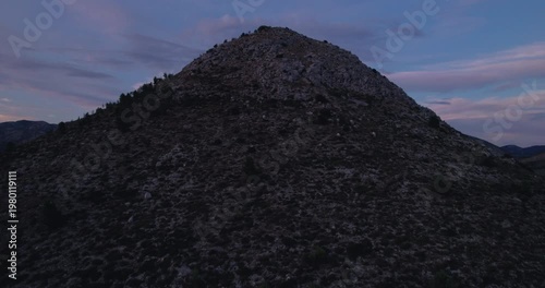 Rocky Mountain Summit At Dusk With Purple Twilight Sky, Granite Ridgeline And Scattered Boulders, Drone Aerial Revealing Remote Wilderness, Moody Cinematic Lighting,
