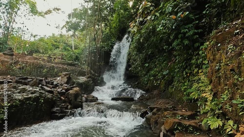 an amazing waterfall in Bali surrounded by green jungles in the afternoon light