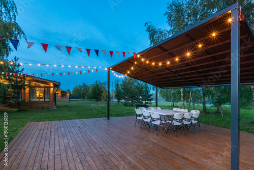 Billede på lærred A gathering space features white chairs arranged around tables under a canopy