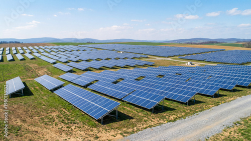Utility Scale Solar Array On Gently Sloping Farmland With Blue Photovoltaic Panels And Distant Hills, Green Power Infrastructure Landscape