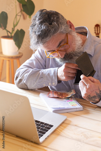 Mature man checking empty wallet having financial problems