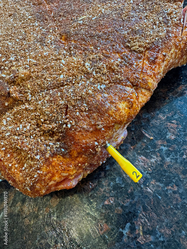Canvas Print View from above a raw Pork Belly or Pork Butt with wireless probe, covered with a dry seasoning rub on a kitchen counter ready for the pellet smoker or grill