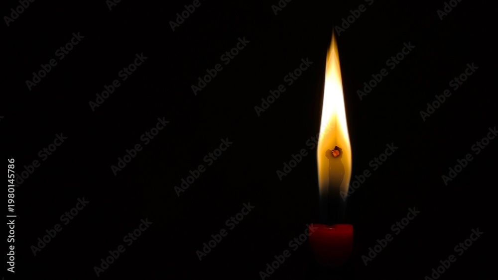Fototapeta premium Photo of a solitary candle flame burning against a deep, solid black background, symbolizing hope, remembrance, prayer, and peaceful atmosphere.
