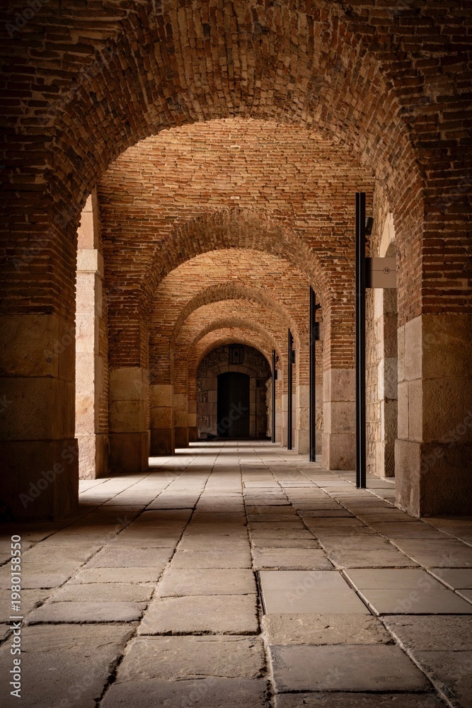 Obraz premium Historic Brick Archway Corridor with Repeating Arches in Barcelona