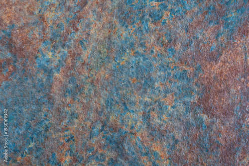 Rough, textured surface with blue and brown color scheme. surface appears to be made of stone or concrete
