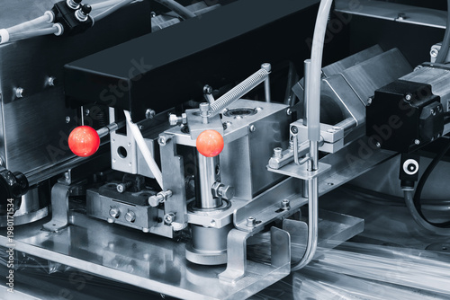фотографія Close-up of industrial automation machinery with metallic components, red knobs, and colorful tubing