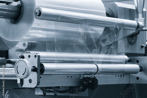 Automatic polyethylene plastic bag production machine with lighting effect. Close-up of the roller of the plastic bag production machine in the light blue scene. product packaging concept