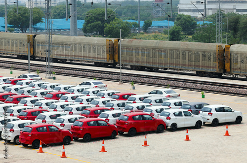 New Cars Lined Up Near Train Tracks for Transport