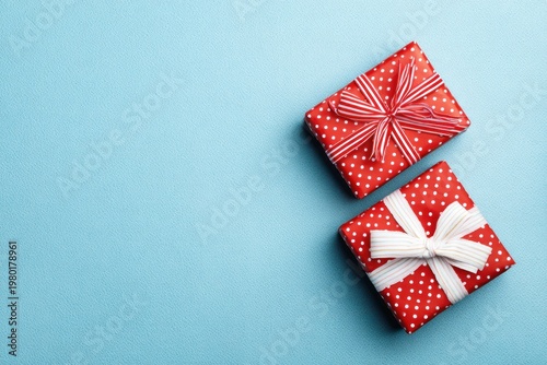 Two red polka dot gifts with ribbons on blue textured background
