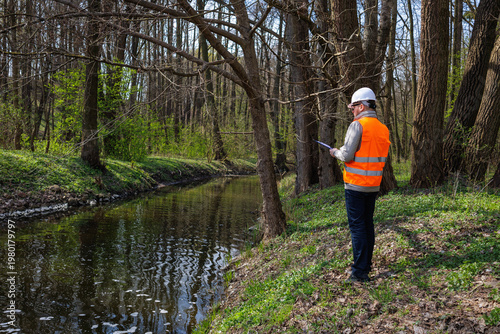 Schilderij op canvas Environmental engineer or ecologist monitoring a forest river condition and water quality