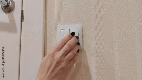 Close-up of a hand turning a light switch on and off. Electricity, energy saving, home automation and everyday household routine. Simple action illustrating power control and lighting.