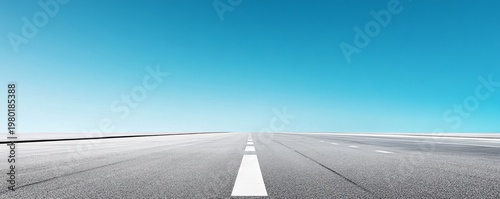 Low angle, minimalist view of an empty asphalt road with leading white lines receding into the horizon under a vast gradient blue sky, symbolizing future journeys and infinite