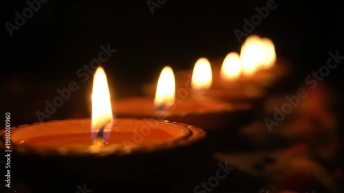Row of lit candles glowing in the dark.