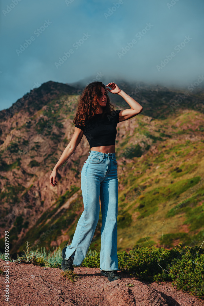 Naklejka premium Brunette woman with wavy hair and athletic figure posing with Kyrgyzstan mountains