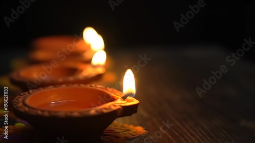 Row of lit diyas on a wooden surface during diwali celebration.
