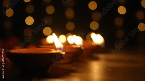 Row of lit diyas with bokeh lights in the background.